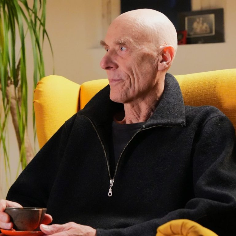 Gerald Weischede | Zen | Psychotherapeut | Göttingen Gerald Weischede sitzt nachdenklich in einem gelben Sessel mit einer Tasse Tee.