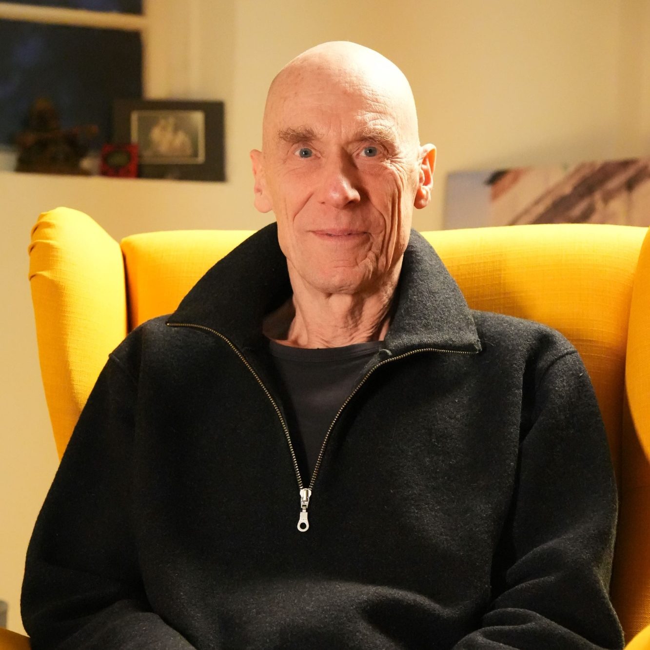 Gerald Weischede | Zen | Psychotherapeut | Göttingen Gerald Weischede sitzt lächelnd in einem gelben Sessel.